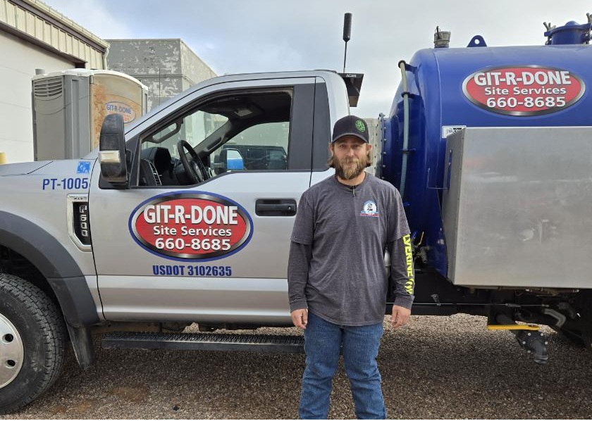 A picture of a service technician in front of a portable toilet service truck