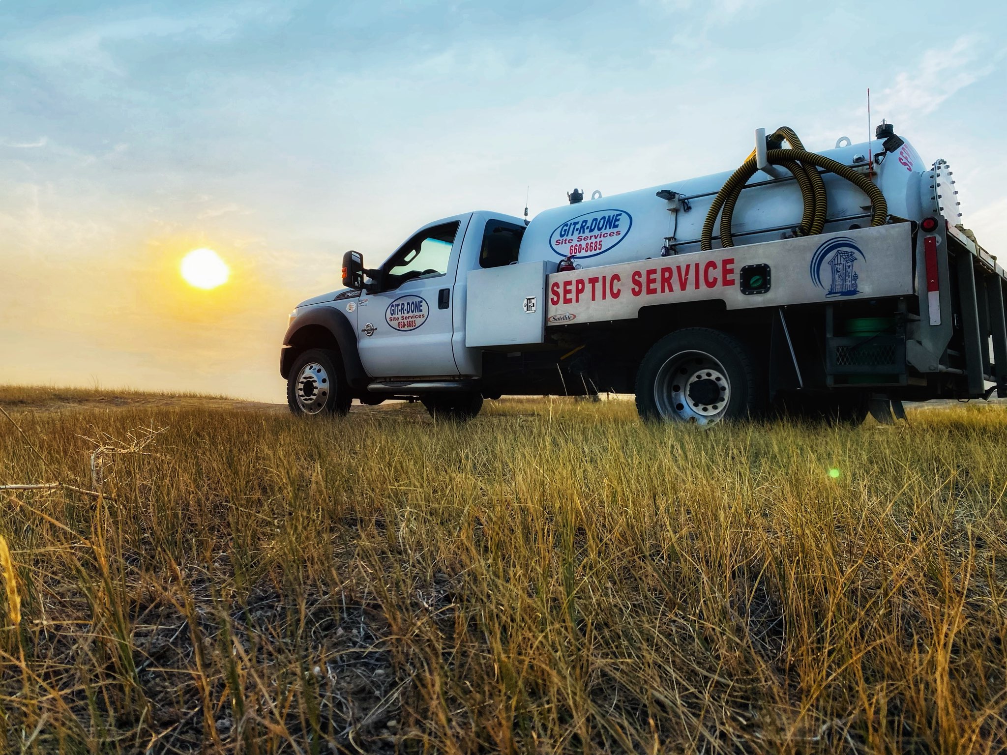 A Portable Toilet Service Truck In Front of a Fall Sunset