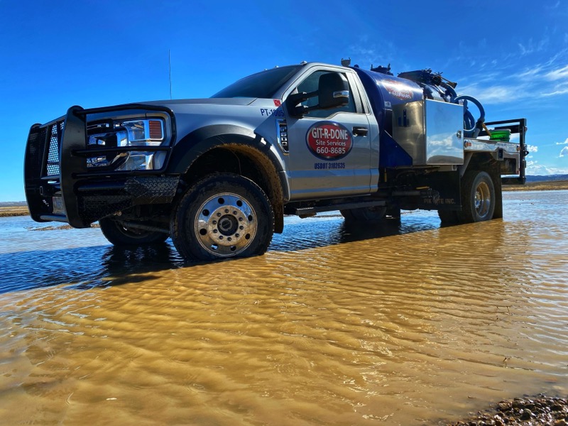 A Portable Toilet Service Truck in a Large Puddle of Water